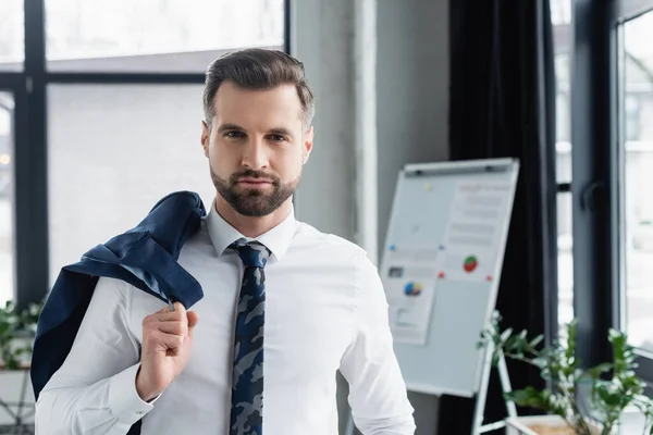 Economist in white shirt holding blazer and looking at camera in office — Stock Photo