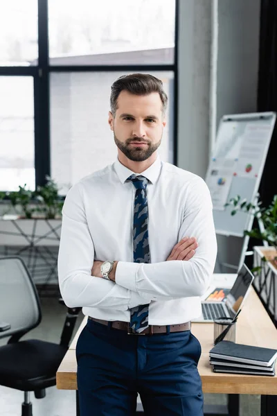 Economist in white shirt standing in office with crossed arms and looking at camera — Stock Photo