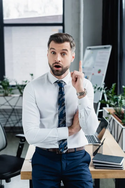 Amazed economist in white shirt showing idea sign and looking at camera — стоковое фото