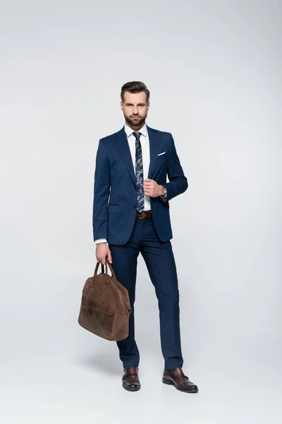 Full length of confident businessman with leather briefcase looking at camera on grey — Stock Photo