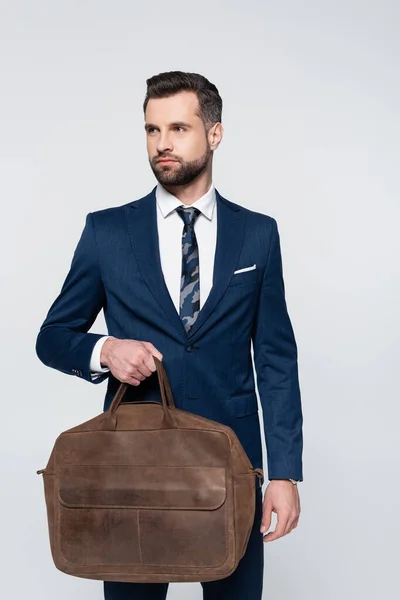 Брюнетка бізнесмен зі шкіряним портфелем дивиться в сторону ізольовано на сірому — стокове фото
