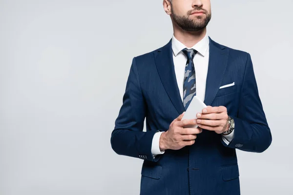 Vista parcial del economista en traje azul sosteniendo teléfono móvil aislado en gris - foto de stock