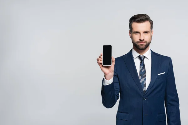 Économiste en usure formelle montrant téléphone portable avec écran blanc isolé sur gris — Photo de stock