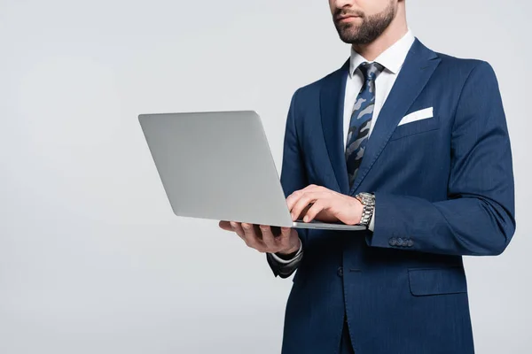 Обрезанный вид бизнесмена в синем блейзере с помощью ноутбука, изолированного на сером — стоковое фото