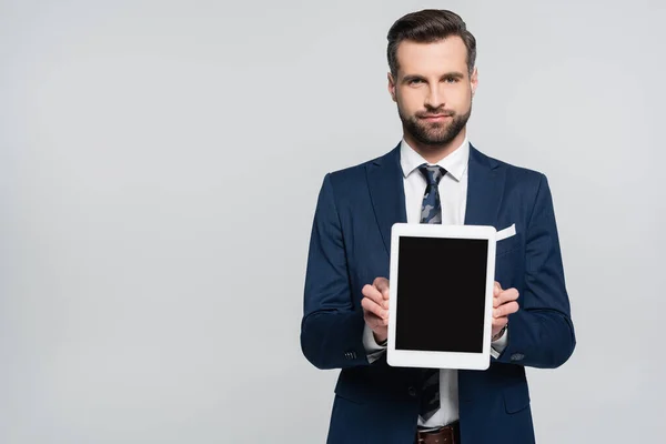 Geschäftsmann im blauen Blazer zeigt digitales Tablet mit leerem Bildschirm isoliert auf grau — Stockfoto