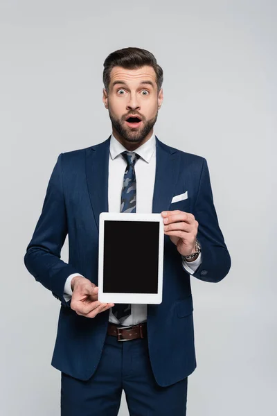 Économiste étonné montrant tablette numérique avec écran blanc à la caméra isolée sur gris — Photo de stock