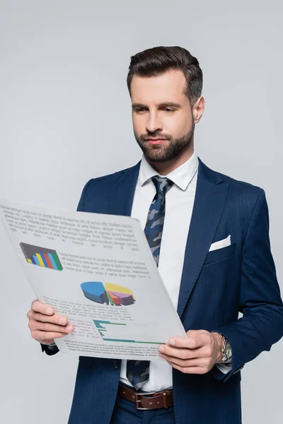 Economista en blazer azul mirando el papel con gráficos aislados en gris - foto de stock