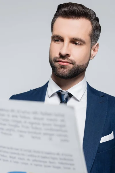 Uomo d'affari barbuto guardando documento sfocato isolato su grigio — Foto stock