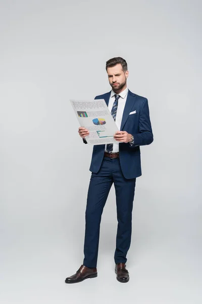Full length view of economist reading document with analytics on grey — Stock Photo