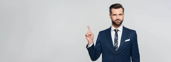 Ökonom im blauen Blazer, der mit dem Finger zeigt, während er isoliert auf graues Banner in die Kamera blickt — Stockfoto