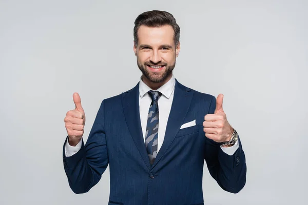 Joyful economist smiling at camera and showing thumbs up isolated on grey — Stock Photo