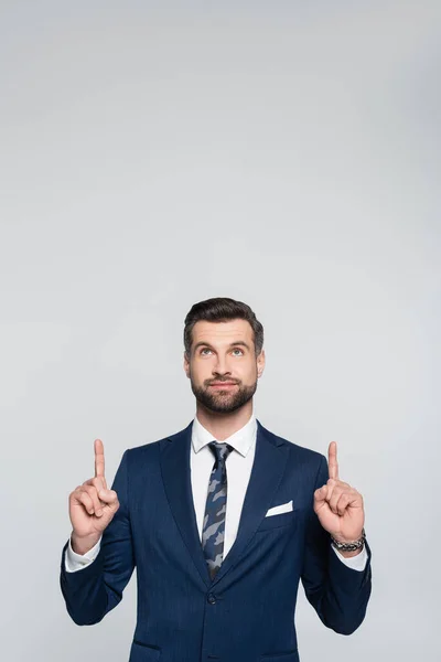Positive economist looking up and pointing with fingers isolated on grey — Stock Photo