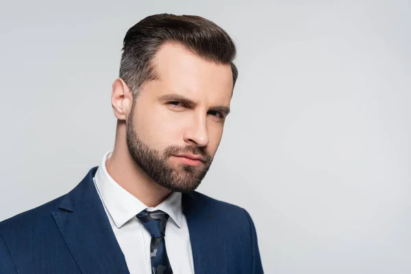 Serio hombre de negocios barbudo mirando a la cámara aislada en gris - foto de stock