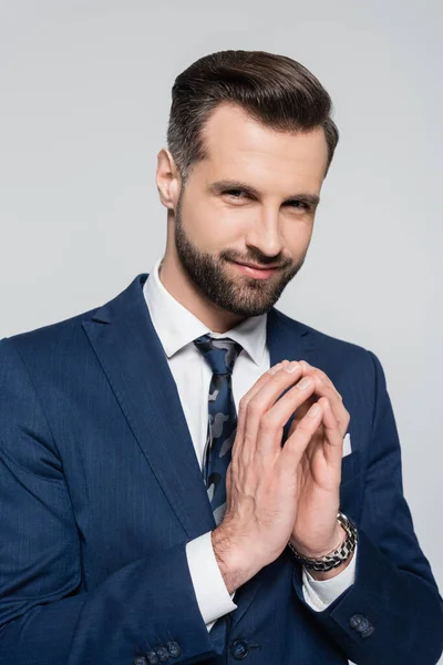 Astuto hombre de negocios en blazer azul sonriendo a la cámara aislado en gris - foto de stock