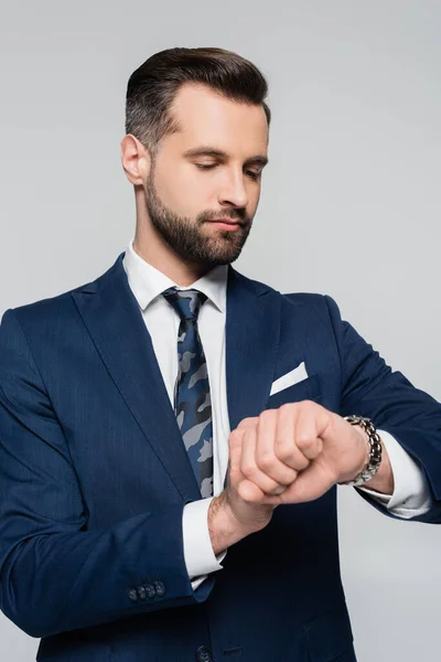 Brünetten Geschäftsmann in blauem Blazer überprüfen Zeit isoliert auf grau — Stockfoto