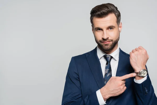 Ökonom zeigt auf Armbanduhr, während er auf Kamera in grau schaut — Stockfoto