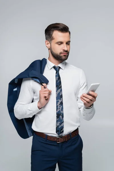 Economista en camisa blanca sosteniendo chaqueta y teléfono inteligente aislado en gris - foto de stock