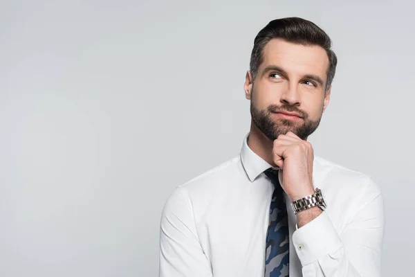 Dreamy and positive economist in white shirt looking away isolated on grey — стоковое фото