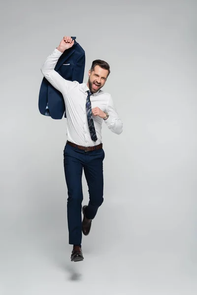 Full length of overjoyed businessman running and shouting on grey — Stock Photo