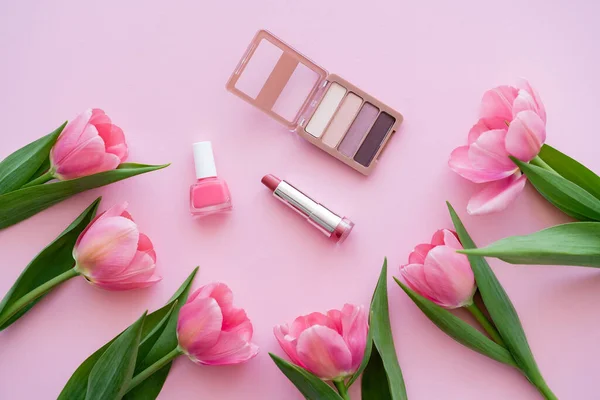 Top view of decorative cosmetics near blooming tulips on pink — Stock Photo