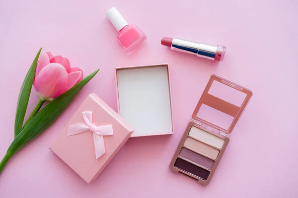 Draufsicht auf blühende Tulpe in der Nähe von Geschenkbox und dekorativer Kosmetik auf rosa — Stockfoto