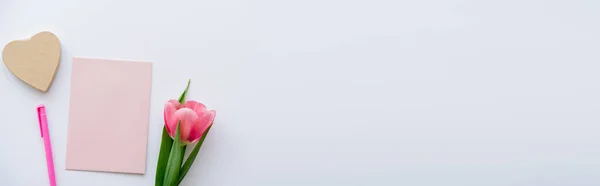 Top view of pink tulip near pastel envelope, pen and craft heart-shaped paper on white, banner — Stock Photo