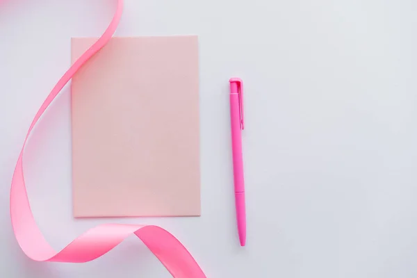 Vue du dessus du stylo près de l'enveloppe et ruban rose sur blanc — Photo de stock