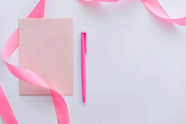 Vue du dessus de l'enveloppe près du stylo et du ruban rose sur blanc — Photo de stock