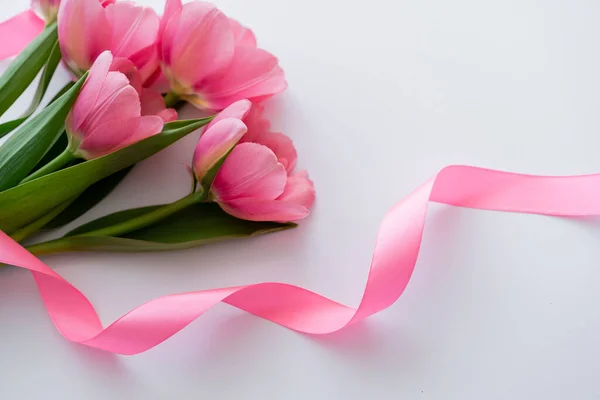High angle view of ribbon near pink tulips on white — Stock Photo