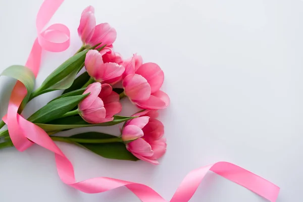 Top view of ribbon near bouquet of pink tulips on white — Stock Photo