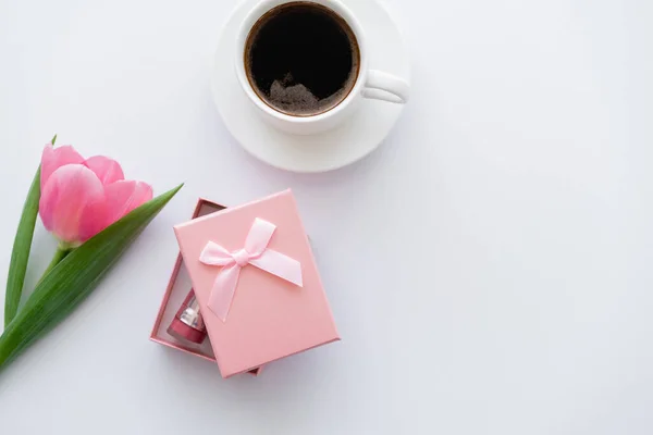 Vue du dessus de tasse de café près de tulipe rose et boîte cadeau sur blanc — Photo de stock