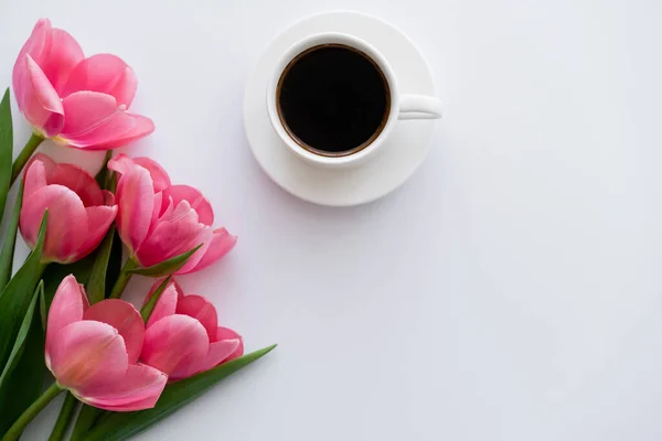 Top view of bouquet of tulips near cup of coffee on white — Stock Photo