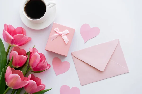 Vista dall'alto di mazzo di tulipani vicino a cuori di carta, busta e scatola regalo su bianco — Foto stock