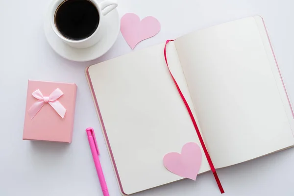 Верхний вид ноутбука с бумажными сердцами и чашкой кофе возле конверта на белом — стоковое фото