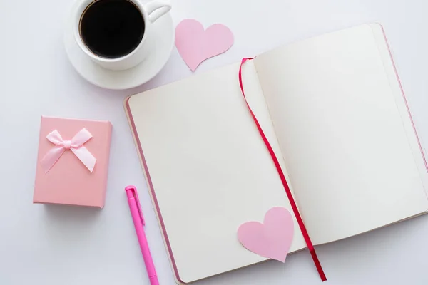 Top view of notebook with paper hearts and cup of coffee near envelope on white — Stock Photo