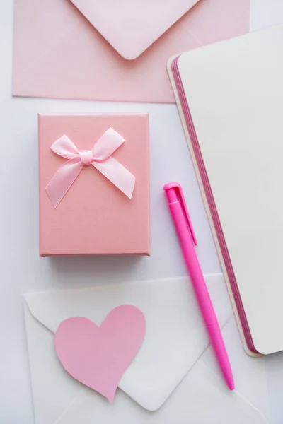 Top view of notebook near envelopes and gift box on white — Stock Photo