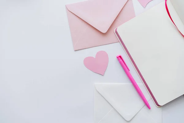 Vista superior del cuaderno cerca del corazón de papel, sobres y caja de regalo en blanco - foto de stock