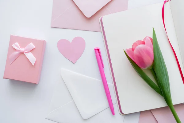 Верхний вид тюльпана на ноутбуке рядом с конвертами и подарок на белом — стоковое фото