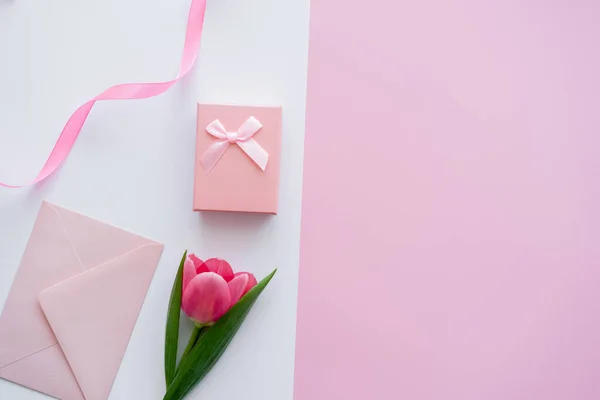 Ansicht des Umschlags in der Nähe von Geschenkbox und Tulpe auf weiß und rosa — Stockfoto