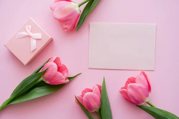 Vue de dessus des tulipes en fleurs près du présent et enveloppe sur rose — Photo de stock