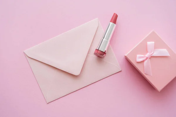 Vista dall'alto del rossetto vicino alla busta e confezione regalo su rosa — Foto stock