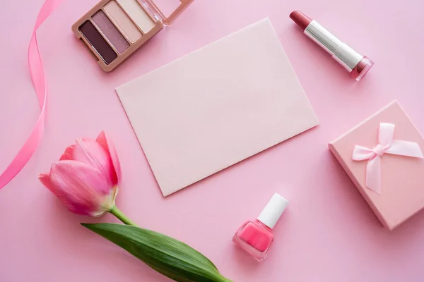 Vista superior da tulipa perto de cosméticos decorativos, envelope e caixa de presente em rosa — Fotografia de Stock