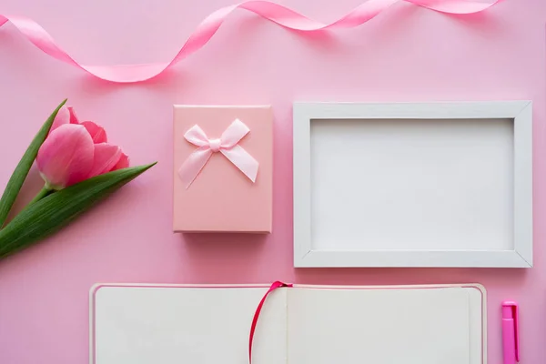 Вид зверху тюльпана біля рамки, порожній блокнот і подарункова коробка на рожевому — стокове фото