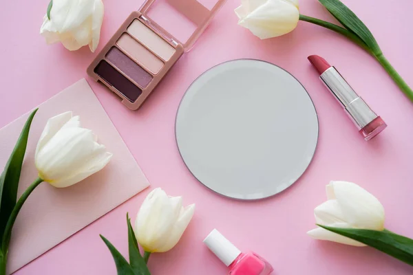 Top view of white tulips on envelope near decorative cosmetics on pink — Stock Photo