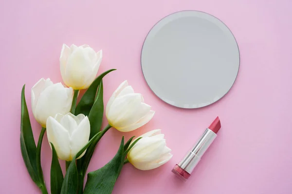 Top view of white tulips near mirror and lipstick on pink — Stock Photo