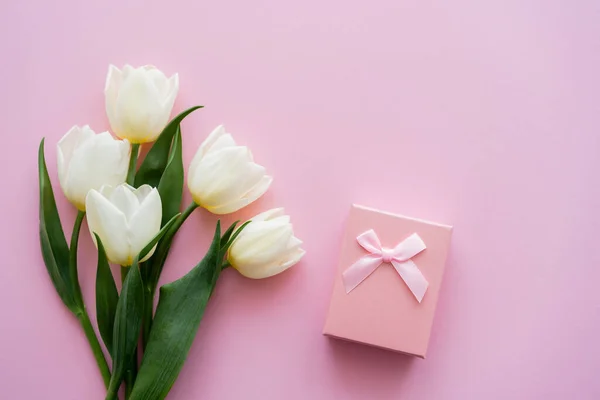 Top view of white tulips near gift box on pink — Stock Photo