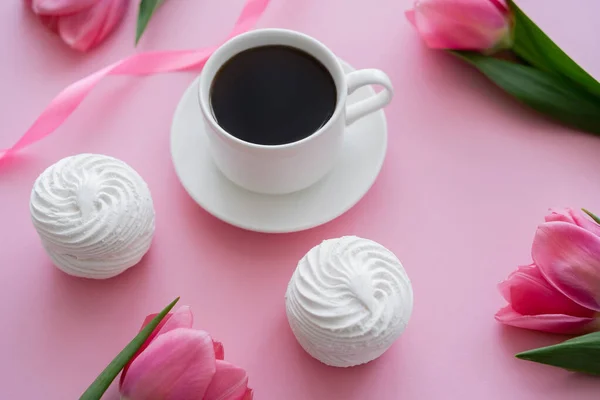 Vue grand angle de tasse avec café près de zephyr et tulipes sur rose — Photo de stock