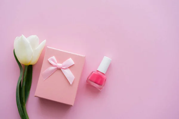 Vue du dessus de la tulipe blanche, boîte cadeau et vernis à ongles sur rose — Photo de stock