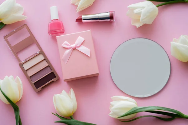 Вид зверху на білі тюльпани, подарункова коробка та декоративна косметика на рожевому — стокове фото