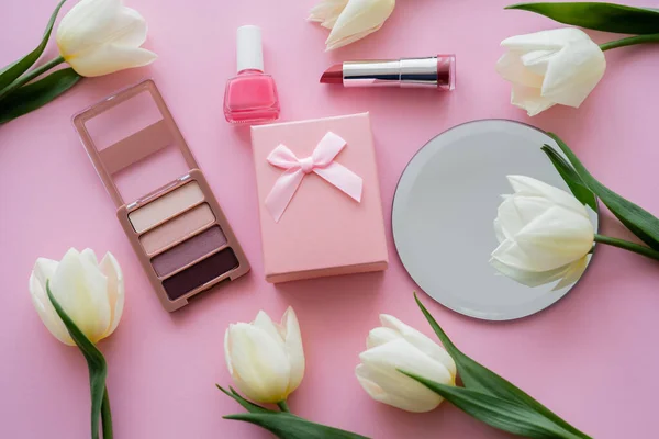 Draufsicht auf weiße Blumen, Geschenkbox und dekorative Kosmetik auf rosa — Stockfoto